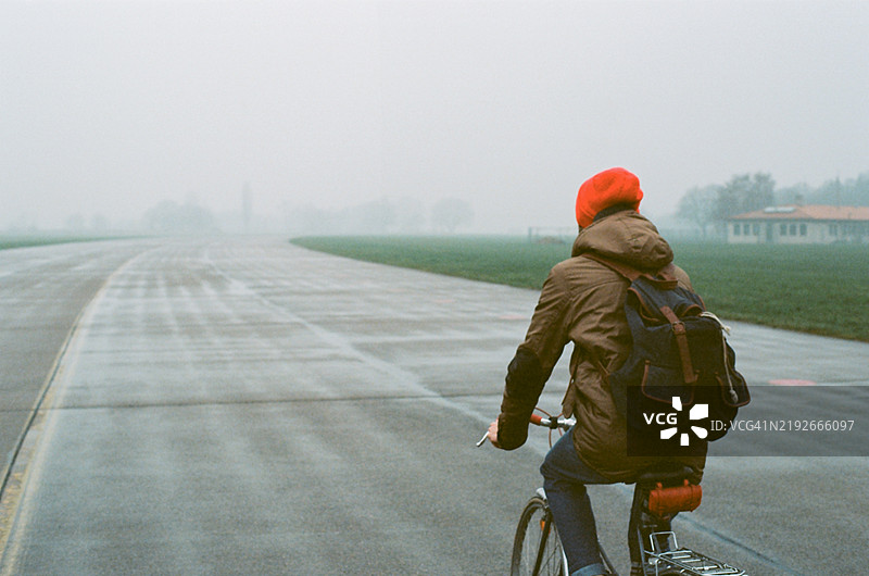 在德国柏林的著名地点——坦佩尔霍夫机场跑道上骑自行车的男子图片素材