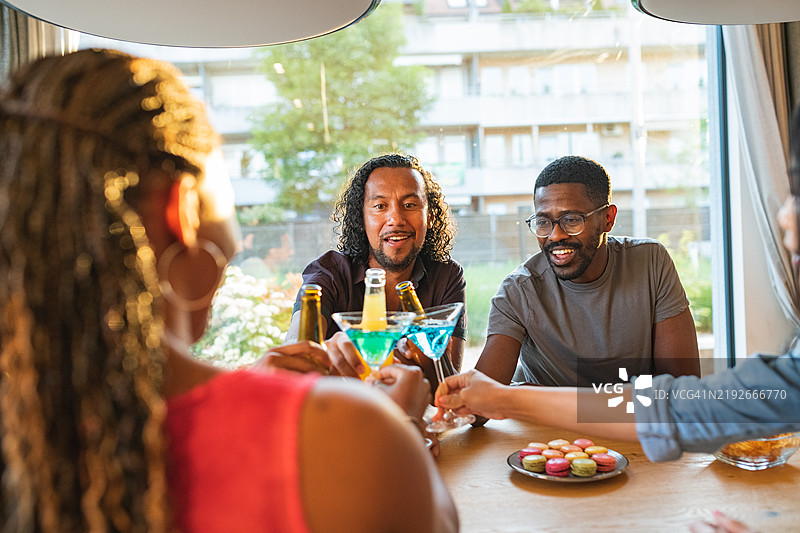 肤色较深的男性与朋友在轻松聚会中举杯庆祝图片素材