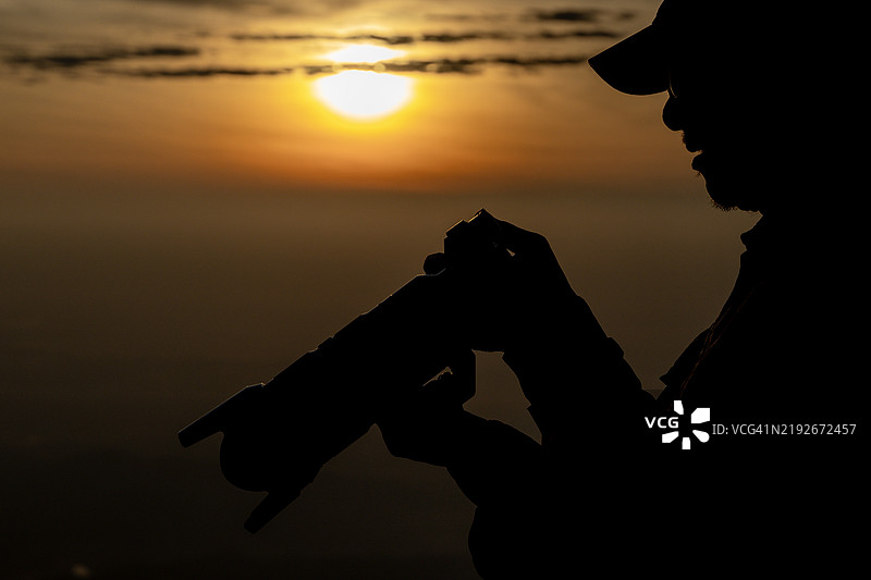 晨曦中，摄影师的剪影与朝阳背景相映成趣图片素材