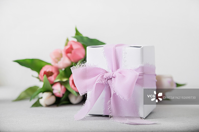 带有粉色丝带和郁金香的礼品盒，背景为浅色图片素材