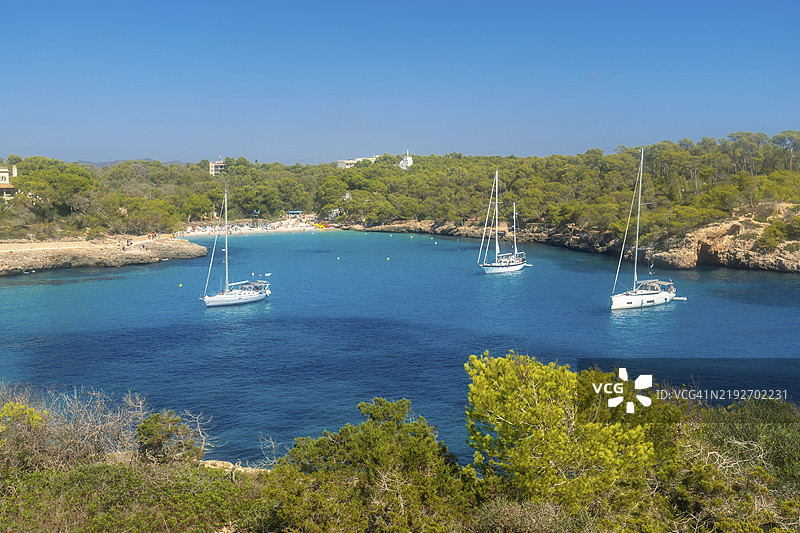 白色帆船停靠在西班牙马洛卡蒙德拉戈自然公园内的美丽海湾卡拉萨马拉多尔的碧绿水面上。图片素材