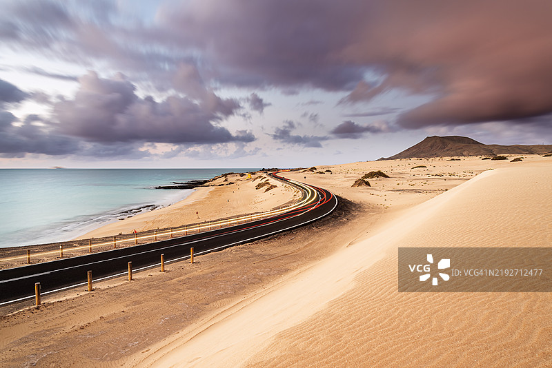 黄昏时分沙漠公路上的汽车尾灯轨迹图片素材