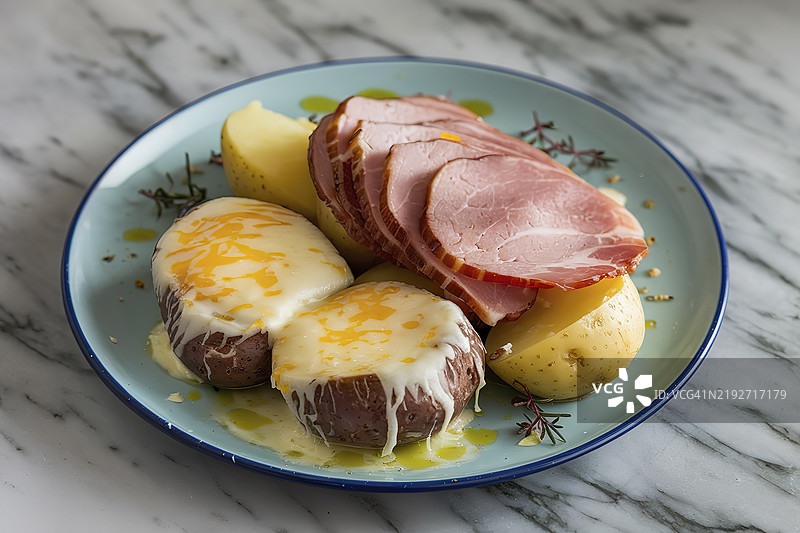 一盘融化奶酪、煮土豆和火腿的照片图片素材