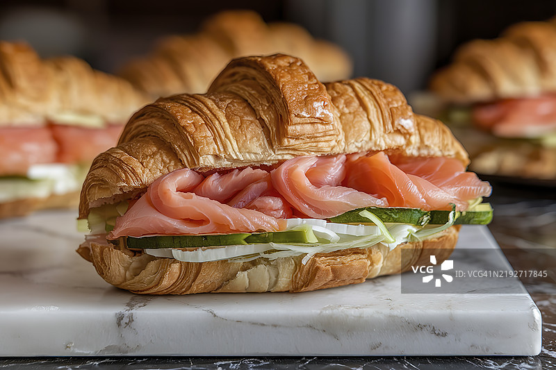 夹有切片三文鱼和蔬菜的可颂三明治图片素材