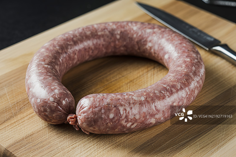 一张生香肠静静放在木砧板上的照片图片素材
