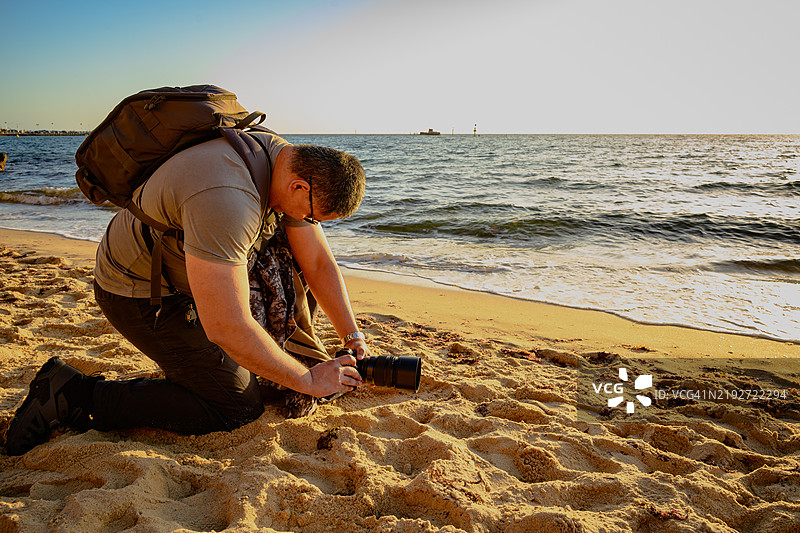 摄影师在澳大利亚维多利亚州墨尔本的海滩上全力以赴拍摄。图片素材