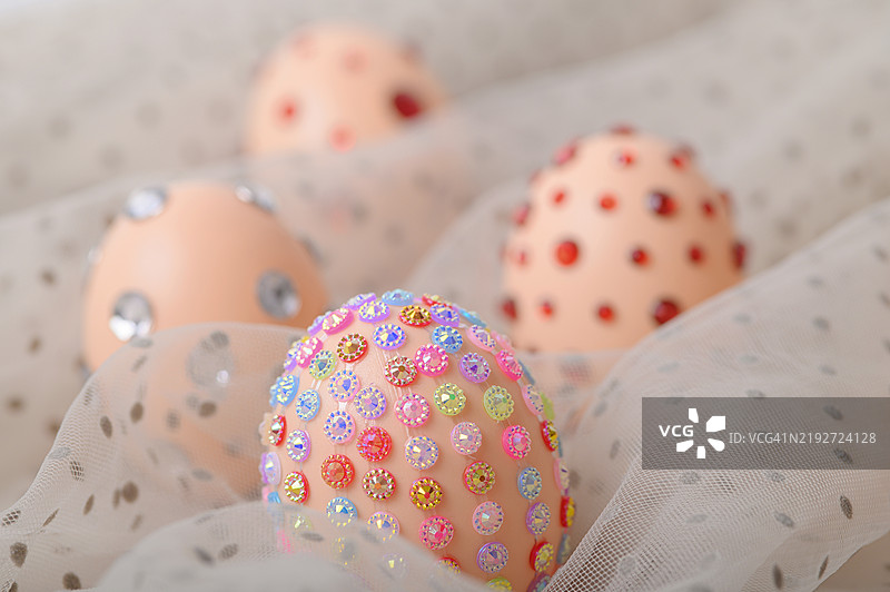 装饰性的复活节彩蛋上镶嵌着五彩缤纷的水晶，背景是优雅的面料图片素材