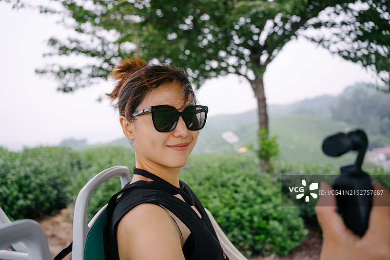 一位年轻的亚洲女性在高山茶园使用运动相机自拍图片素材