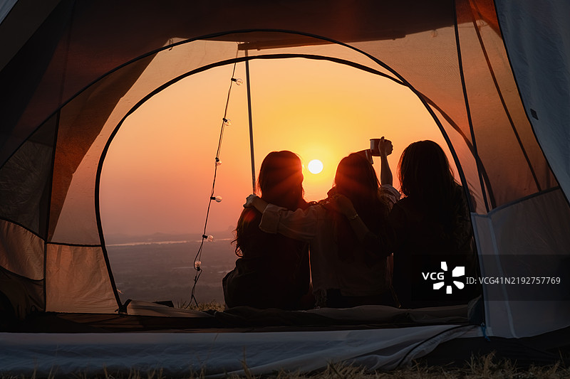 一群年轻的亚洲朋友在夏季露营假期中快乐地在帐篷里聊天。自由、休闲、旅行、冒险的概念。图片素材