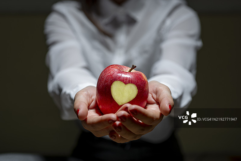 女人手持一个心形的苹果图片素材