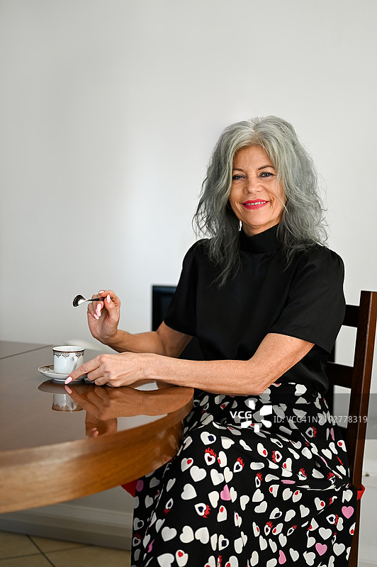 一位手握茶杯的老年女性肖像。图片素材