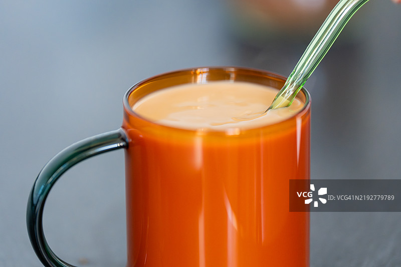 橙色咖啡杯和可重复使用的玻璃吸管放在桌子上图片素材