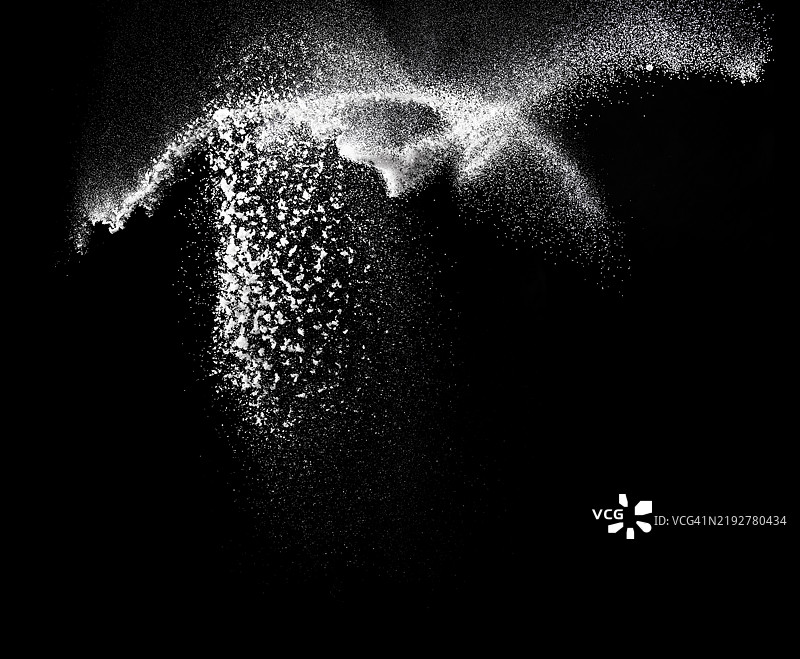 厨房里黑色背景下糖粒飘落的云彩。图片素材