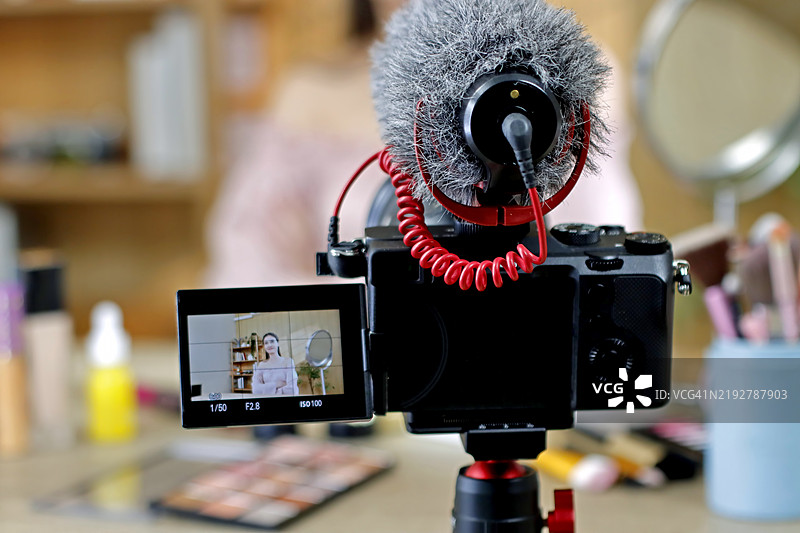 女孩视频博主或美容博主为订阅者录制视频，讲解如何使用面霜并分享相关信息。图片素材