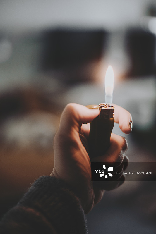 一个人，一只肤色浅的手，指甲修剪整齐，正握着一个打火机。图片素材