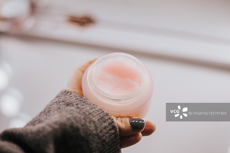 女性手部涂抹面部抗衰老霜。浴室提供了充足的空间。图片素材