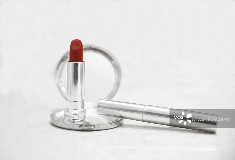 一支非常红的口红和一些金属包装的美容产品图片素材
