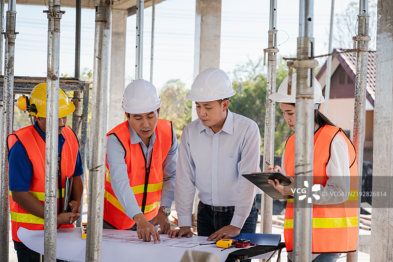 土木工程团队与建筑师和工头一起在施工现场查看蓝图并规划建筑的施工。图片素材