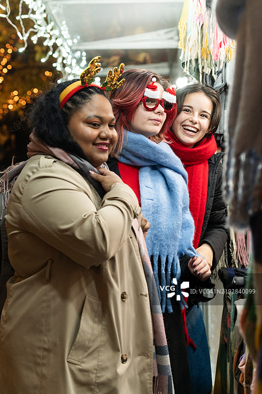 三位年轻女性在圣诞市场上微笑并享受乐趣图片素材