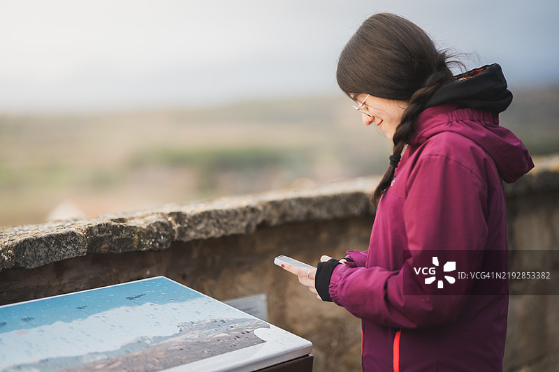 年轻女性在观景点查看地图时使用手机图片素材