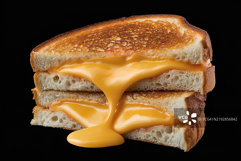 一张切成两半的烤奶酪三明治的照片，里面有融化的奶酪。图片素材