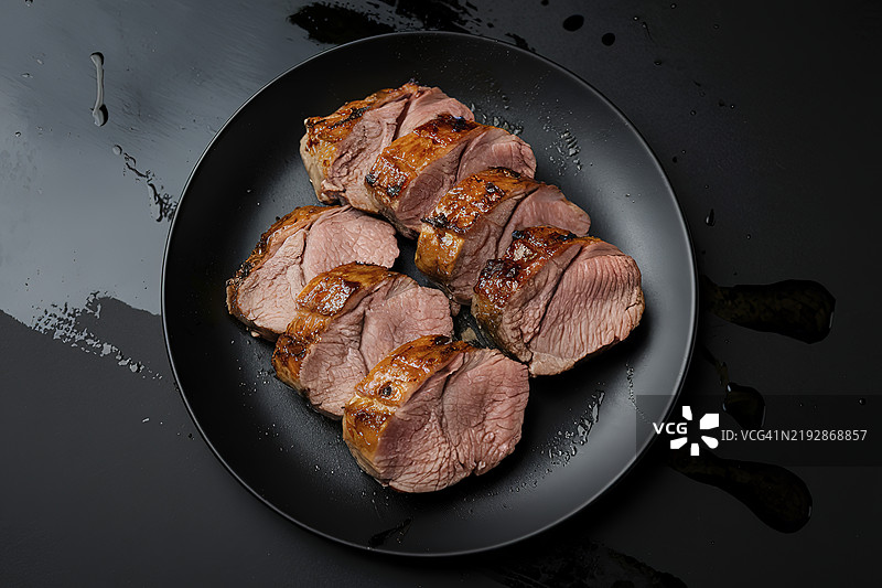 一盘带有金棕色外壳的烤肉片，背景为黑色图片素材