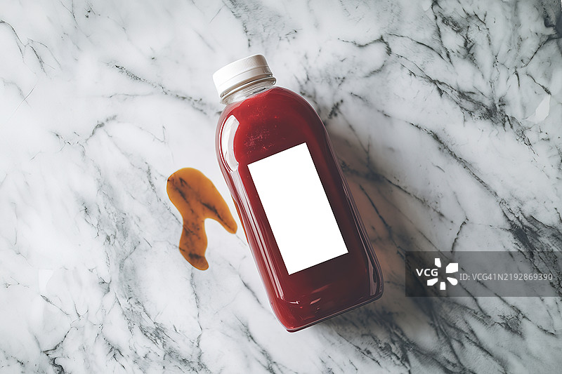 一张装有红色果汁的塑料瓶照片，背景为大理石纹理。图片素材