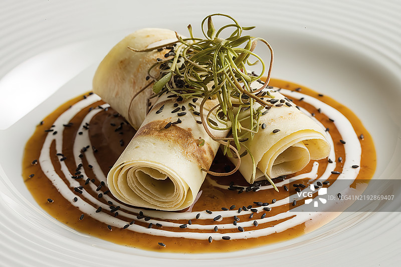 薄饼卷放在白色酱汁上图片素材