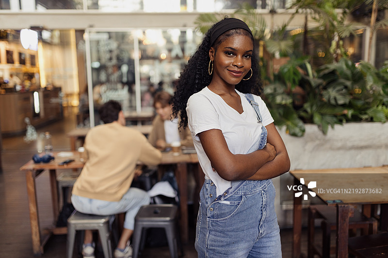 自信的女性在现代咖啡馆中微笑，周围是城市风格的装饰图片素材