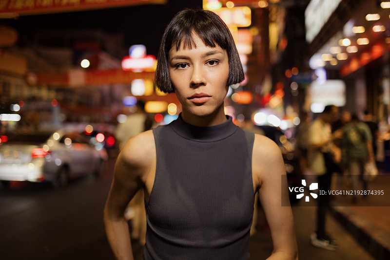 夜晚，勇敢的女性在热闹的城市街道上行走图片素材