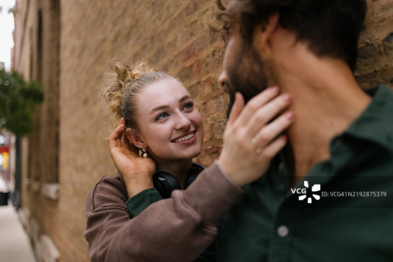 幸福的情侣在砖墙旁分享浪漫时刻图片素材