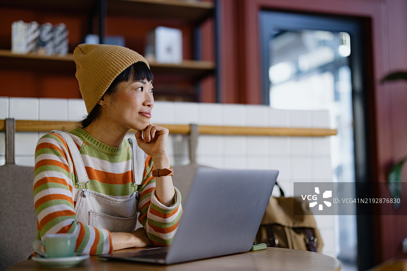 创意人士在咖啡馆放松，使用笔记本电脑工作图片素材