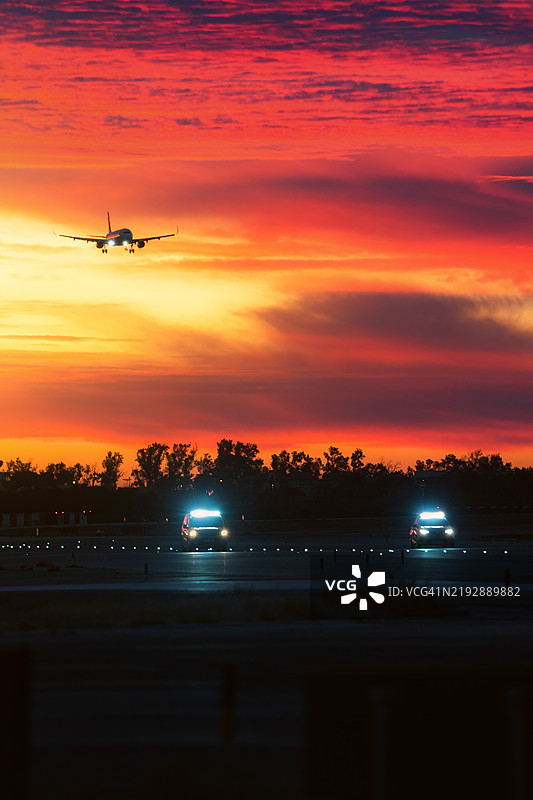 飞机在黎明时分降落，地面引导员正在检查跑道。图片素材