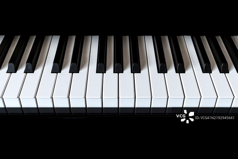 黑色背景下的钢琴和钢琴键盘。图片素材