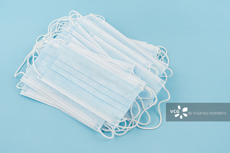 医用口罩，蓝色背景下的医用防护口罩。一次性外科口罩覆盖口鼻。图片素材