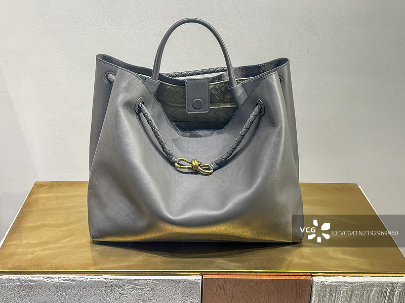 灰色皮革手提包，带编织手柄图片素材