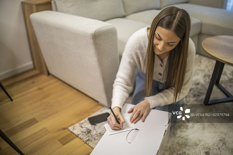 可爱的女性正在包裹上写下送货地址，准备送给客户。图片素材