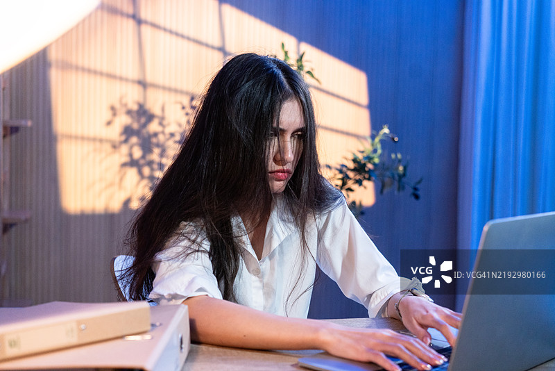 专注的女性在夜间使用笔记本电脑打字图片素材