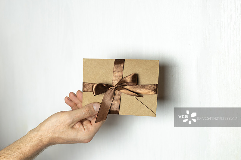 男性手持棕色证书，配有棕色缎带，礼品券，优惠券，折扣图片素材