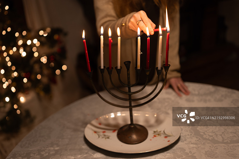 女性手部特写点燃光明节的哈努基亚蜡烛，庆祝光明节的第八个晚上 - 股票照片图片素材