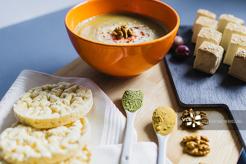 健康的素食午餐或晚餐，奶油香辣蔬菜汤，米饼，熏豆腐奶酪，橄榄，核桃，咖喱，姜和小麦草或螺旋藻。图片素材
