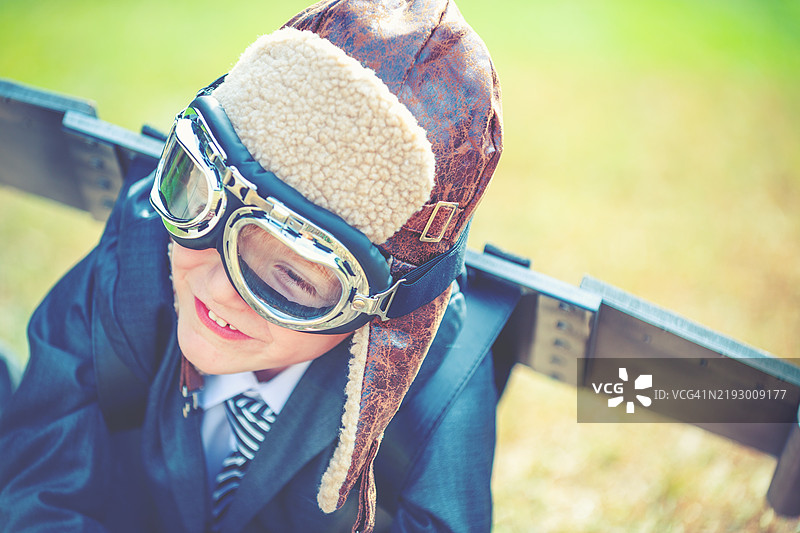 抱负，创新商业理念。一个穿着西装和自制传统飞行员服装的小孩。图片素材