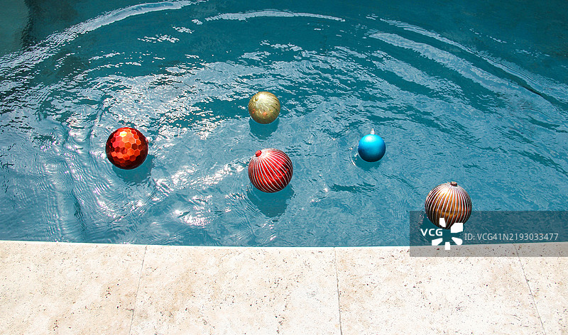 闪亮多彩的圣诞装饰品漂浮在游泳池边缘附近图片素材