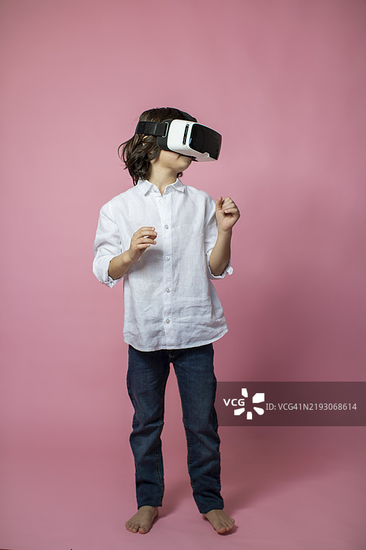 孩子在粉色背景下享受虚拟现实体验图片素材