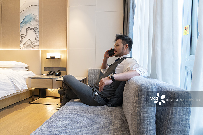 一位商人在酒店房间的沙发上打电话图片素材