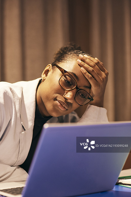 伤心的女商人用手托着头，盯着笔记本电脑。图片素材