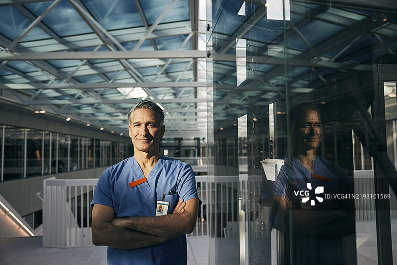 自信的老年男性医生在医院里双臂交叉的肖像图片素材