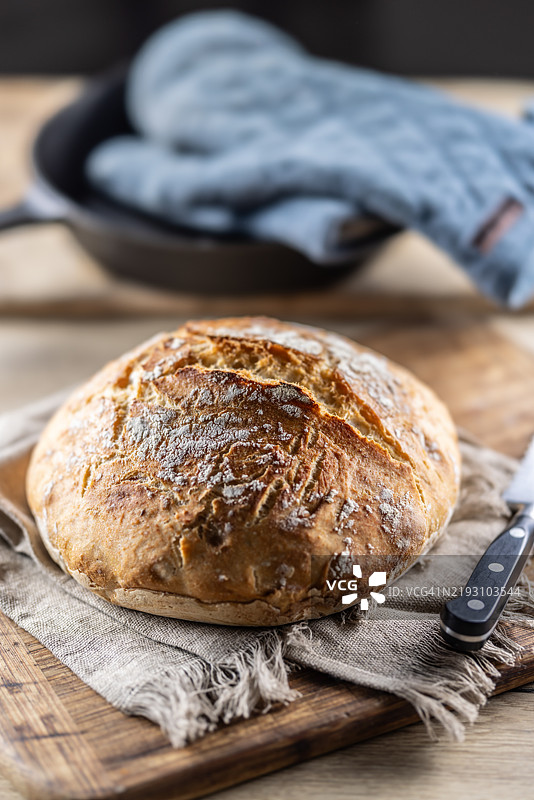 新鲜的脆皮面包放在切菜板上。图片素材
