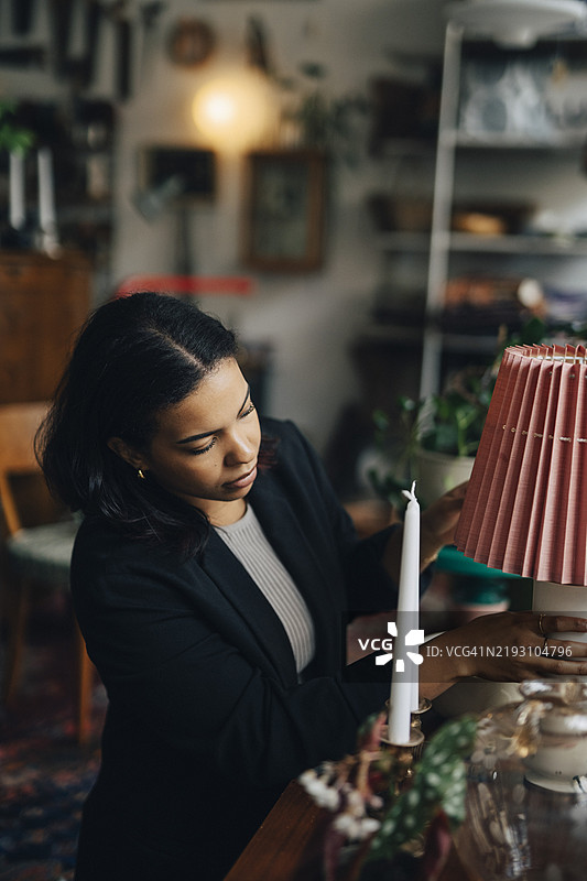 年轻女老板在古董店里整理灯具。图片素材