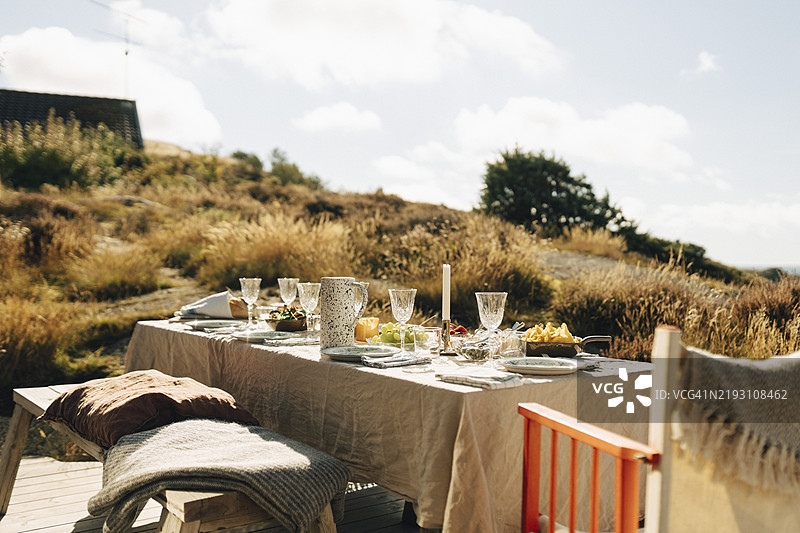 阳光明媚的日子里，桌上摆放着餐具的美食布置图片素材